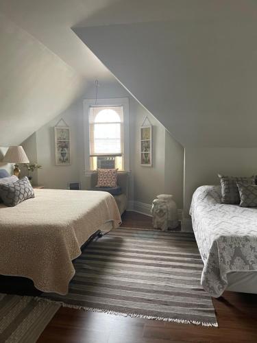 a attic bedroom with two beds and a window at Redefined Alchemy LLC in Little Falls