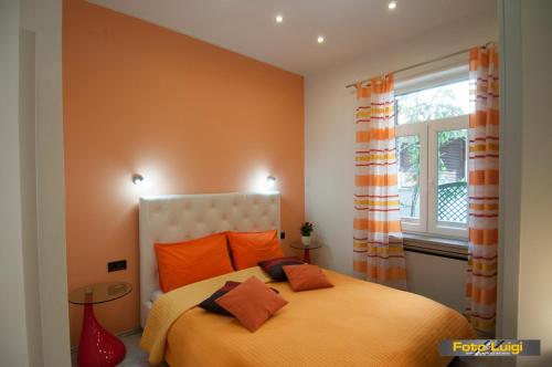 1 dormitorio con 1 cama con almohadas de color naranja y ventana en Apartments KOMEL I, en Opatija