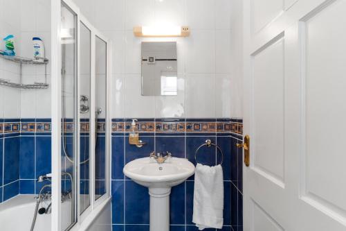 y baño azul y blanco con lavabo y ducha. en Private Room with Private Entrance., en Galway