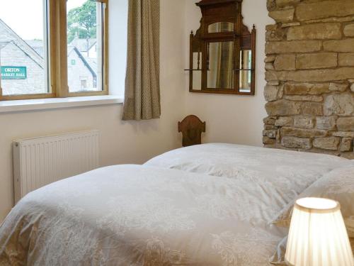 Una cama blanca en un dormitorio con una pared de piedra. en Cumberland House en Orton