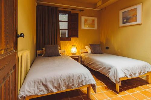 2 camas en una habitación con paredes amarillas en La masovería de Mas Redortra, en Sant Pere de Torelló