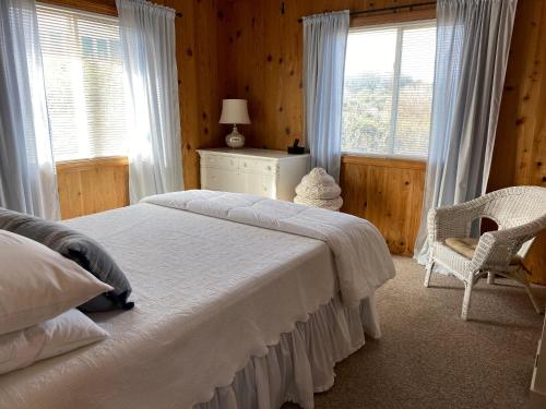 une chambre avec un lit, une chaise et des fenêtres dans l'établissement Summersalt, à Southern Shores