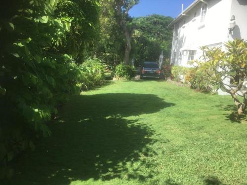 a yard of a house with a car parked in it at Spacious White House Villa 1 minute to sandy beaches in Saint James
