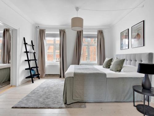 a white bedroom with a large bed and windows at Sanders Stage - Endearing Three-bedroom Apartment Near Nyhavn in Copenhagen