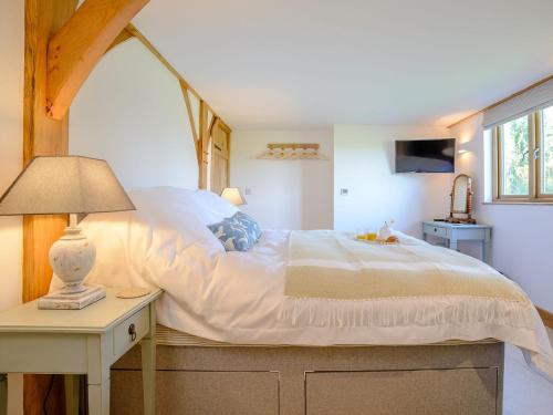 een slaapkamer met een bed en een tafel met een lamp bij Hares Furrow - Uk12607 in Burton Overy