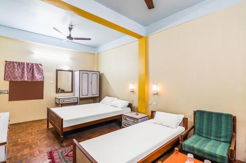 a room with two beds and a chair and a mirror at Hotel Florence in Siliguri
