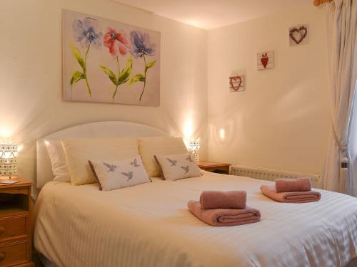 een slaapkamer met een wit bed en handdoeken bij Cockleshell Cottage in Cockermouth