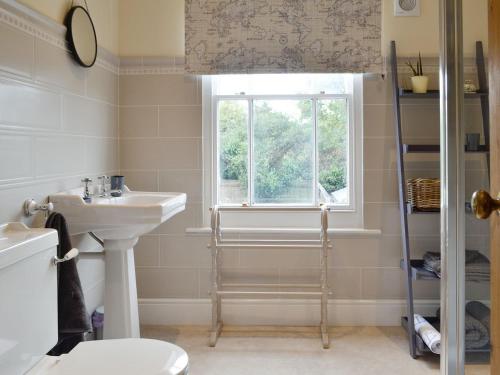 baño con lavabo y aseo y ventana en Cats Cottage, en Kessingland
