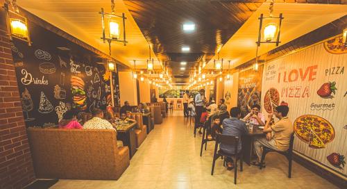 Hotel Elite Palace في Comilla: مجموعة من الناس يجلسون على الطاولات في المطعم