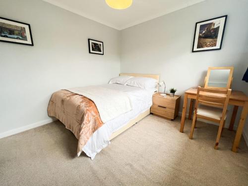 a bedroom with a bed and a chair and a table at Home away from home Milngavie in Milngavie