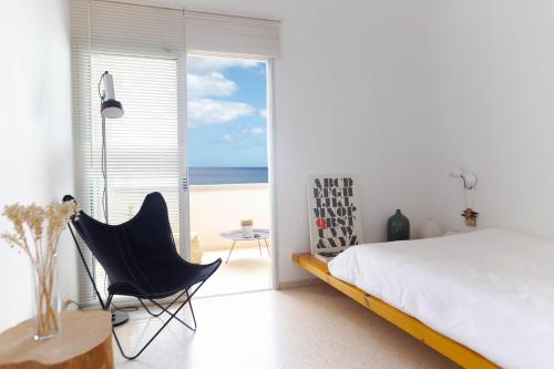 a bedroom with a bed and a chair and the ocean at Beach hideaway apartment with modernist design in Santa Cruz de Tenerife