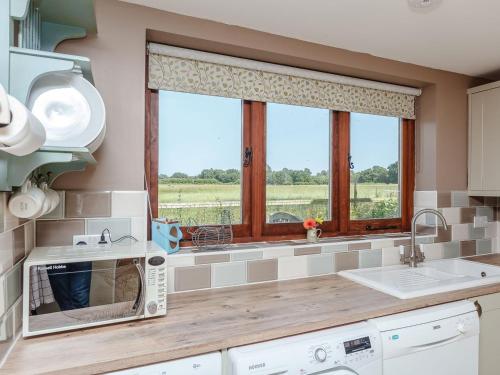 uma cozinha com um balcão com um micro-ondas e uma janela em The Barn em Coldwaltham