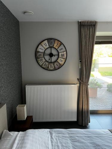 a clock hanging on a wall next to a window at Parel van Bever - Perle de Biévène in Bever