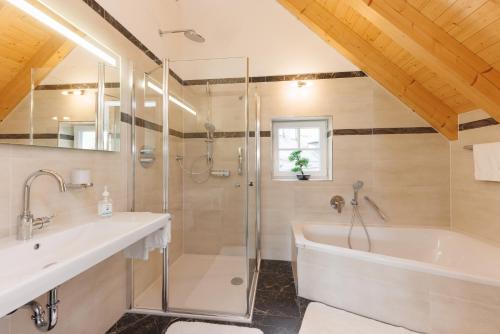 a bathroom with a shower and a tub and a sink at Lahntalhotel Feudingen in Bad Laasphe