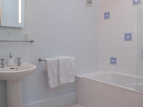 La salle de bains blanche est pourvue d'un lavabo, d'une baignoire et de toilettes. dans l'établissement Beats Cottage, à Llangwm