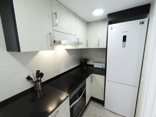 cocina con armarios blancos y nevera blanca en Apartamento New Tarraco en Tarragona