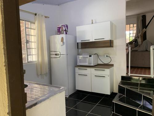 a kitchen with a white refrigerator and a microwave at Chácara com Piscina, Churrasqueira, Salão de Jogos, Campo futebol in Itariri