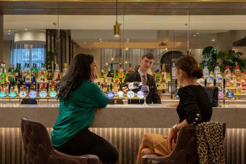 two women sitting at a bar with a bartender at Crowne Plaza Dublin Airport, an IHG Hotel in Santry