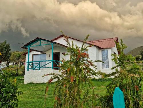 a small white house with a blue roof at Casa Campestre Sua Meca Guatavita in Guatavita