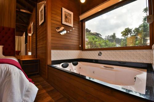 a bathroom with a large window and a bath tub at Stillo Gramado Dutra in Gramado