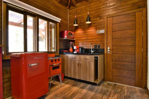 Cabaña de madera con cocina con nevera roja. en Stillo Gramado Dutra, en Gramado