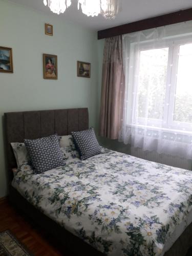 1 Schlafzimmer mit einem Bett mit einer Blumendecke und einem Fenster in der Unterkunft Cozy, central 1-bedroom apartment in Timisoara, Romania in Timişoara