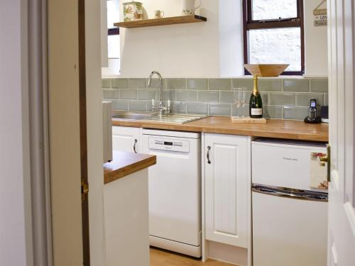 a kitchen with white cabinets and a sink at Rose Cottage in Lofthouse