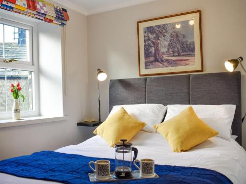 a bed with a blue blanket and yellow pillows at Rose Cottage in Lofthouse