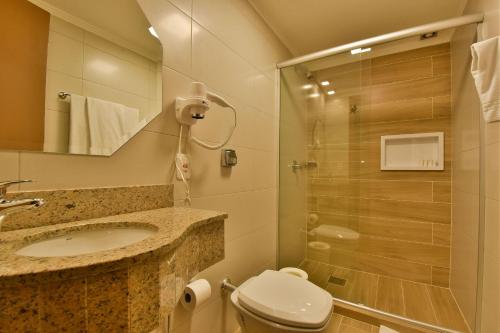 uma casa de banho com um chuveiro, um WC e um lavatório. em Stillo Gramado Aconchego em Gramado