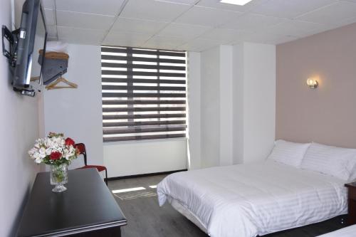 a bedroom with a bed and a table with a vase of flowers at Hotel Italia in Cuenca