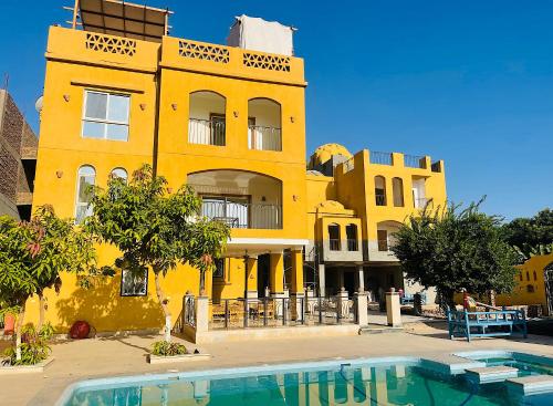 a yellow building with a pool in front of it at Jewel Howard Carter Hotel in Luxor