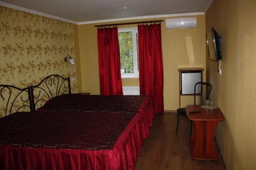 a bedroom with a bed and a window with red curtains at Hotel Gostynnyi Dvir in Bucha