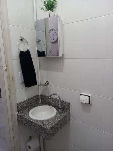 ein Badezimmer mit einem Waschbecken und einer Uhr an der Wand in der Unterkunft FLAT LOCAÇÃO TEMPORADA NO CENTRO DE ITAPIRA in Itapira