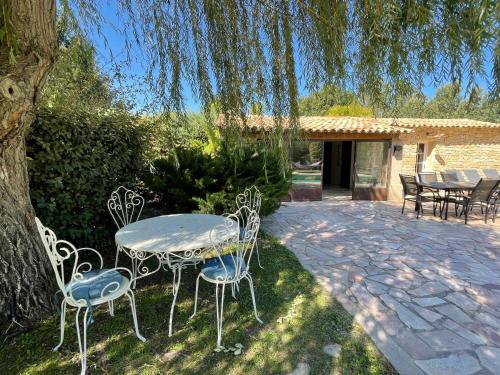 een patio met een tafel en stoelen onder een boom bij FUVOLEA, Maison de vacances à 15 min du centre d'Aix-en-Provence, piscine chauffée en saison - jardin - parking privé gratuit in Fuveau