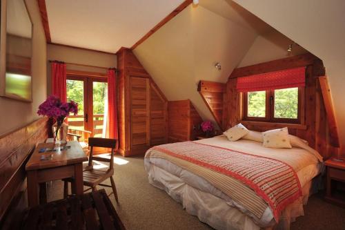Petrohue Lodge في بيتروهي: غرفة نوم بسرير ومكتب ونوافذ