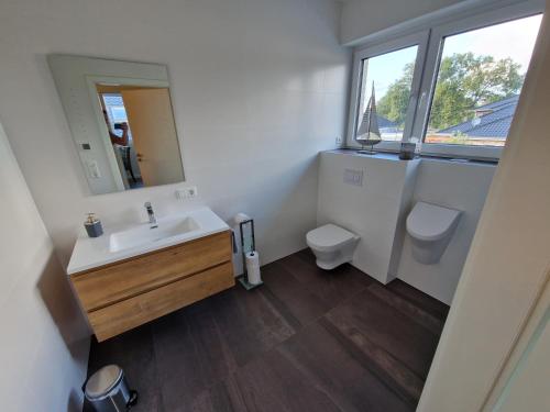 ein Badezimmer mit einem Waschbecken, einem WC und einem Spiegel in der Unterkunft Apartment nahe Meyer Werft in Ostfriesland mit Küche & Netflix in Westoverledingen