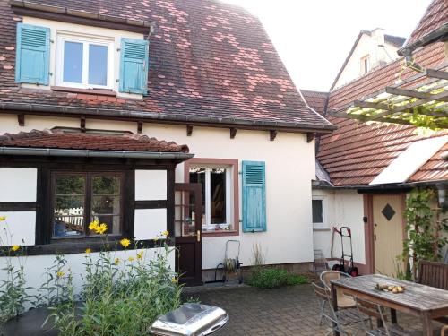 una casa bianca con persiane blu e un patio di Familiensuite, zwei Zimmer, Mitbenutzung von Küche und Bad a Rott