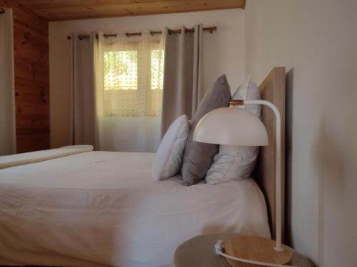 a bedroom with a bed with a lamp and a window at Le Chalet jacuzzi et Détente 4 Étoiles in Bagnères-de-Bigorre