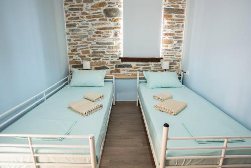 two beds in a room with a brick wall at Με θέα το ηλιοβασιλεμα 2 in Afissos