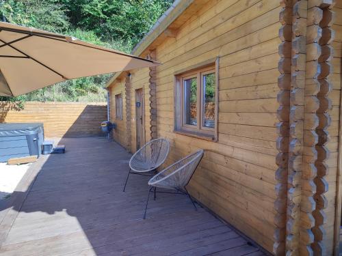 a wooden deck with two chairs and an umbrella at Le Chalet jacuzzi et Détente 4 Étoiles in Bagnères-de-Bigorre
