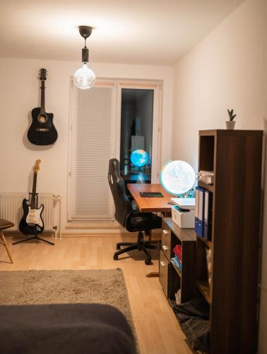 Pokój z biurkiem, krzesłem i gitarą w obiekcie Ruhiges Apartment mit großem Balkon und Stellplatz w Lipsku