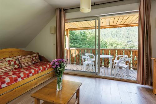 a bedroom with a bed and a balcony with a table at Lagrange Vacances Le Domaine des 100 Lacs in Cauterets