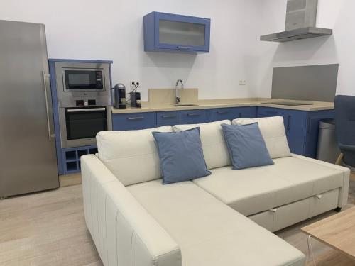 a white couch with blue pillows in a kitchen at MonKeys Apartments Pagés del Corro Triana in Seville