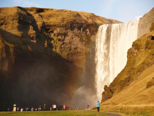 a group of people standing in front of a waterfall at Vestri Pétursey in Vestri Pétursey