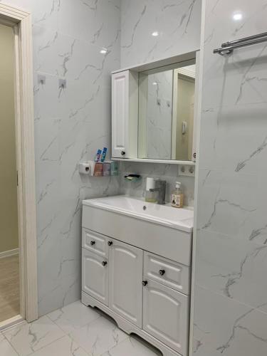 W białej łazience znajduje się umywalka i lustro. w obiekcie Апартаменты на Назарбаева w mieście Ałma-Ata