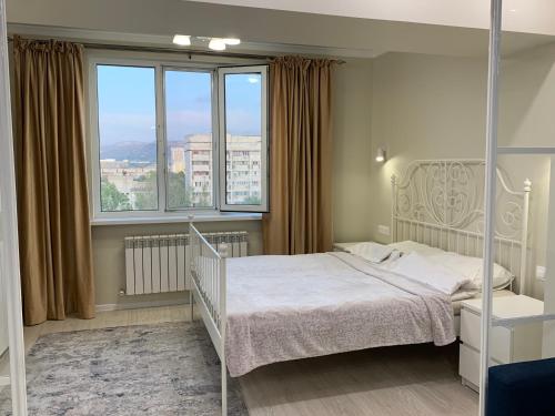 um quarto com uma cama branca e uma grande janela em Апартаменты на Назарбаева em Almaty