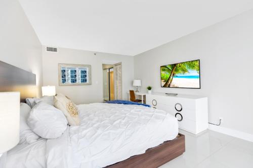a white bedroom with a large bed and a tv at Biscayne Bay Blues in Miami