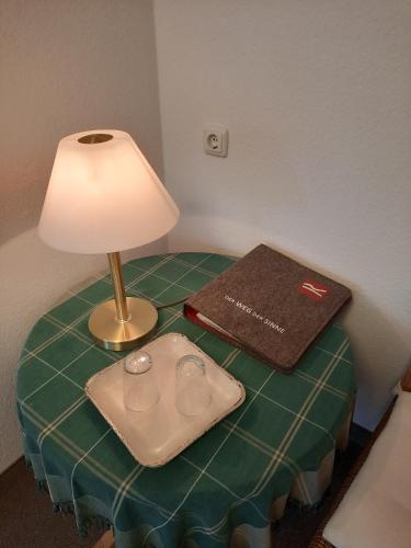 a table with a lamp and a book on it at Lauras Landhauspension in Medebach