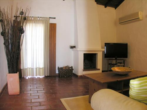 a living room with a couch and a tv at Herdade Do Freixial - Turismo Rural in Vila Nova de Milfontes