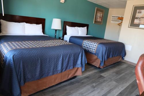 Duas camas num quarto com paredes azuis e pisos em madeira em Budget Inn em Alamogordo